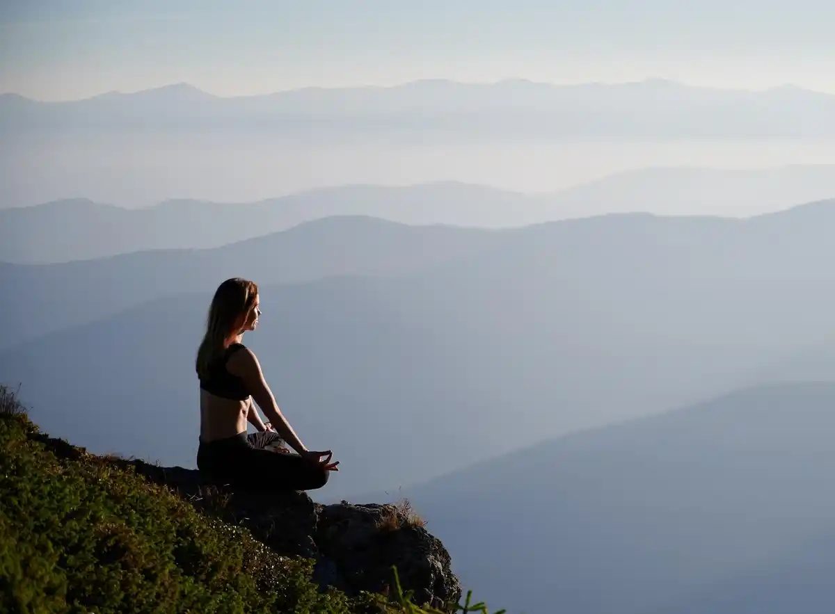 calm person meditating at desk with nature view