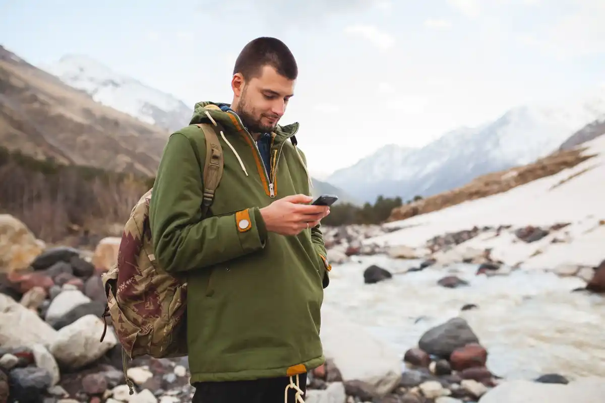 happy traveler with backpack using smartphone navigation outdoors