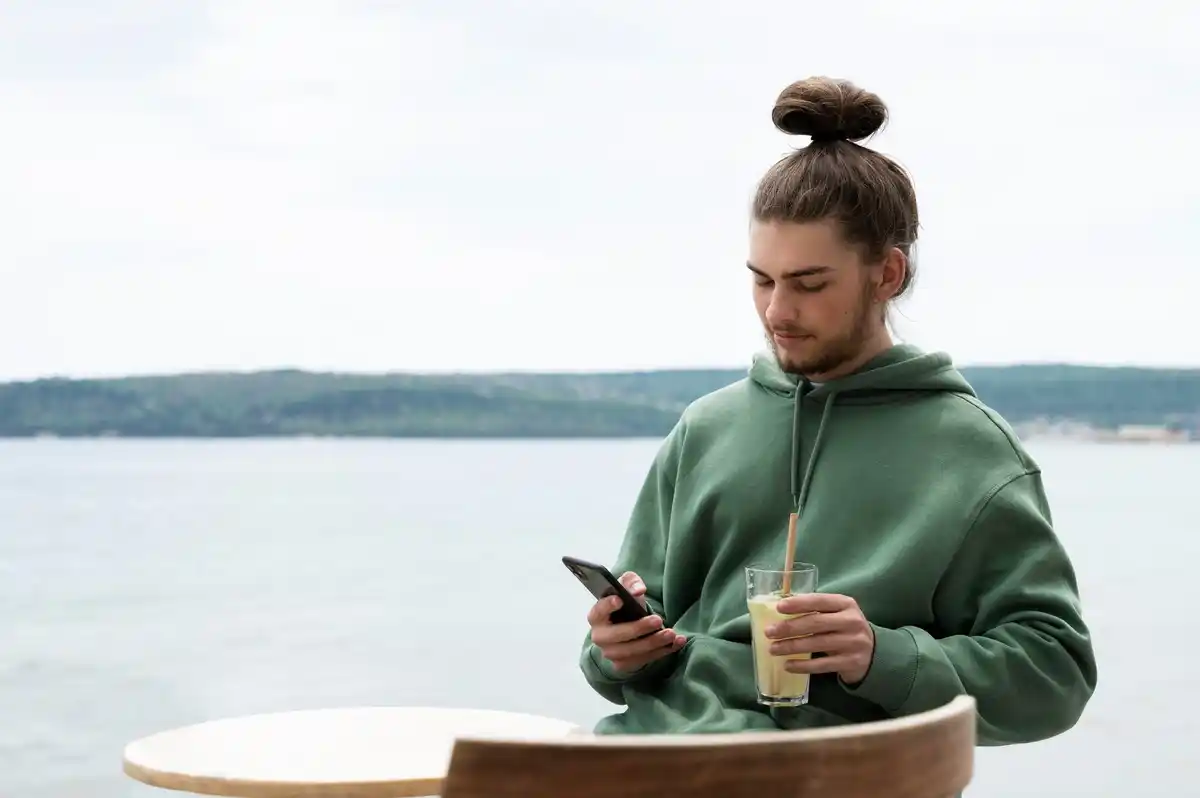 person taking a break outdoors with coffee and phone
