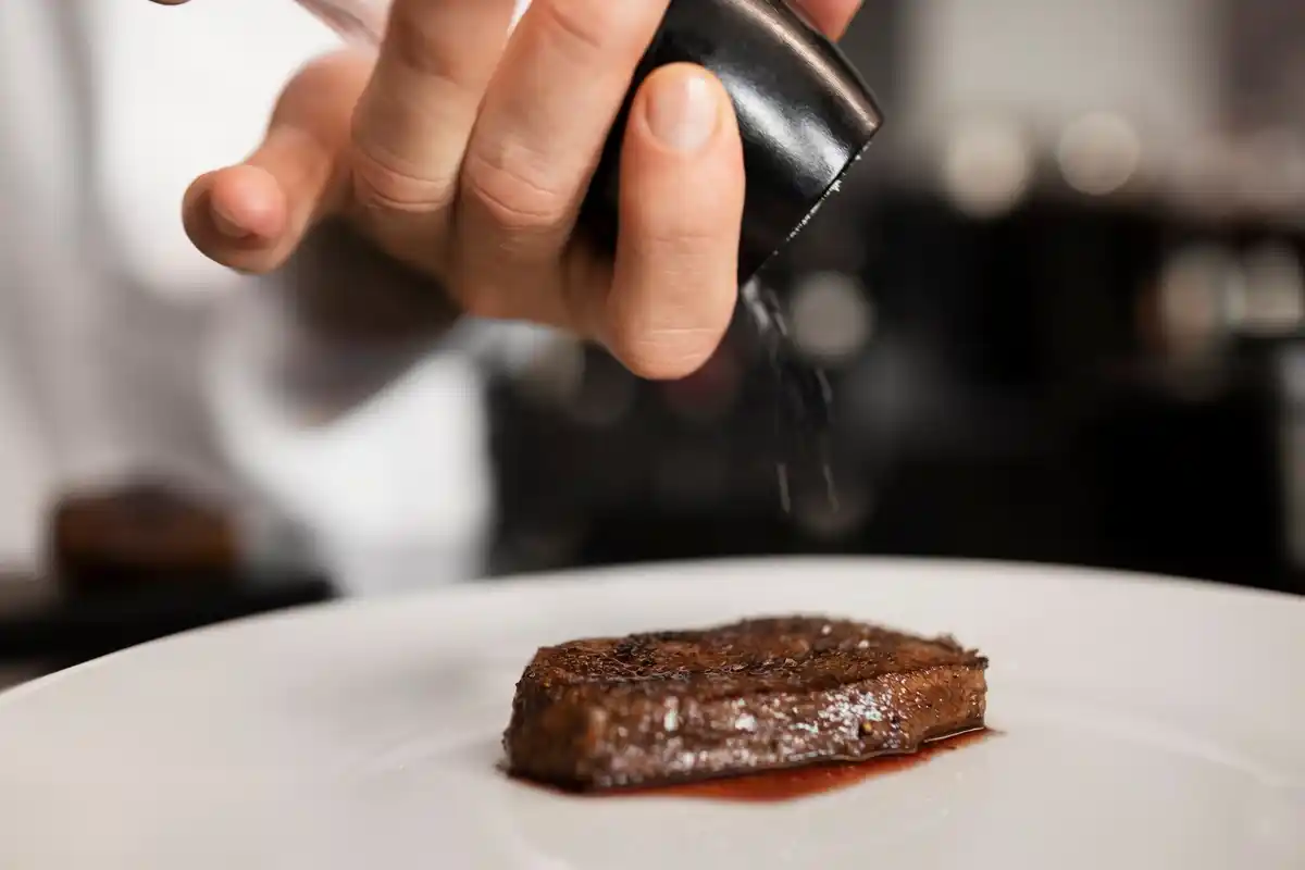 chef sprinkling coarse sea salt on steak