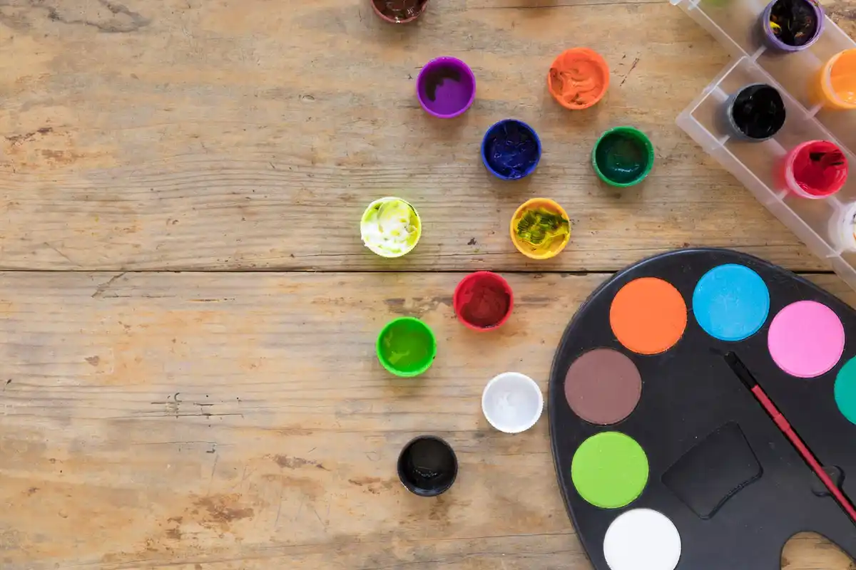 colorful paint palette with brushes on work table