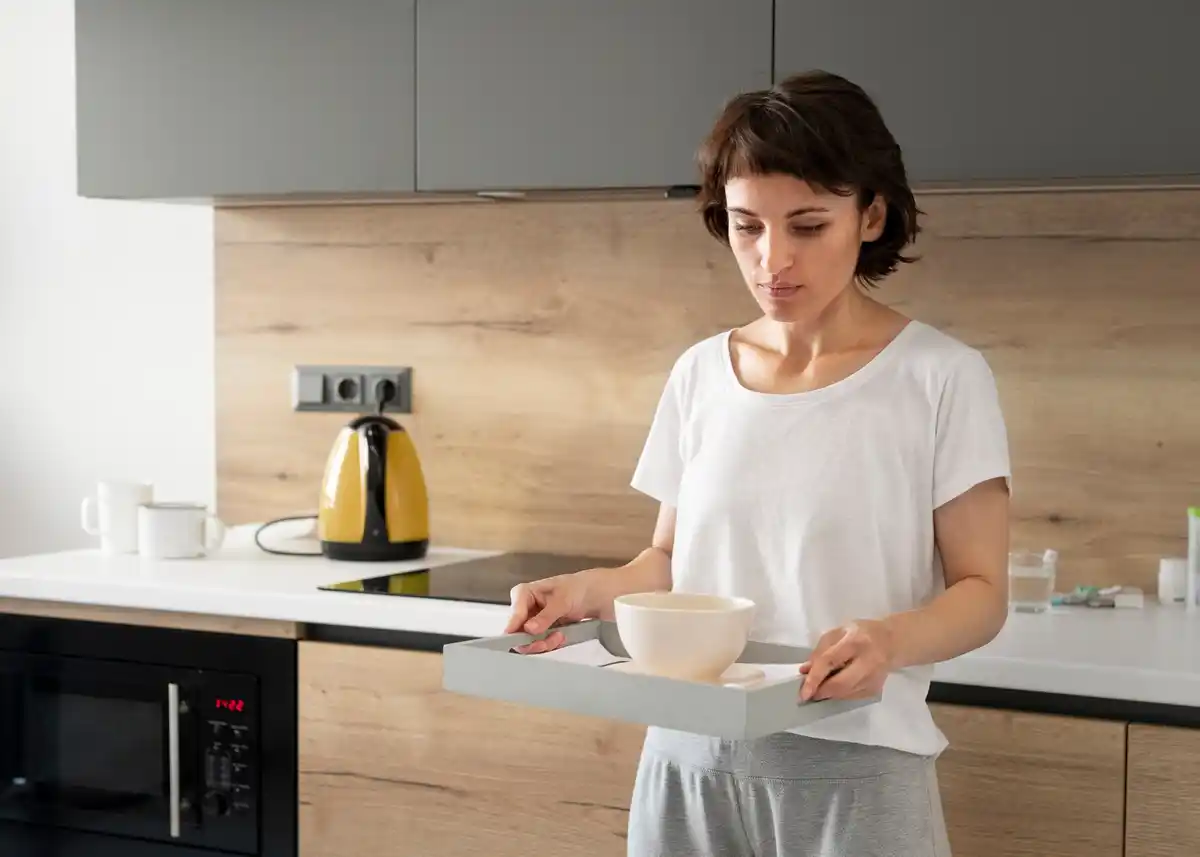 person tidying kitchen countertop with storage boxes