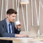 focused person working at desk with coffee and laptop