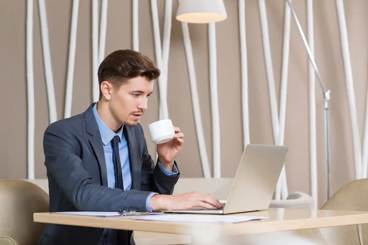 focused person working at desk with coffee and laptop