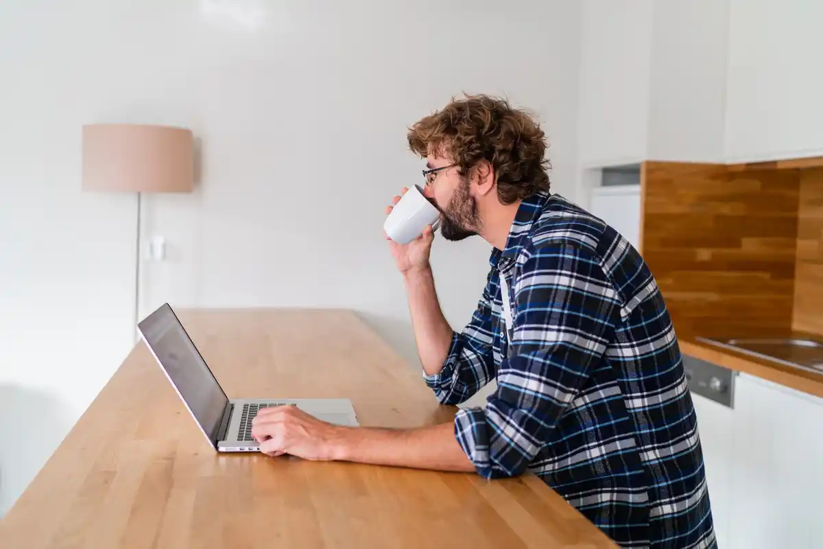 focused person at cluttered desk with coffee and laptop
