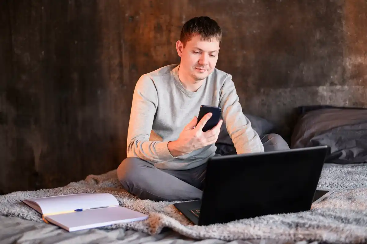 person putting phone away while working on laptop