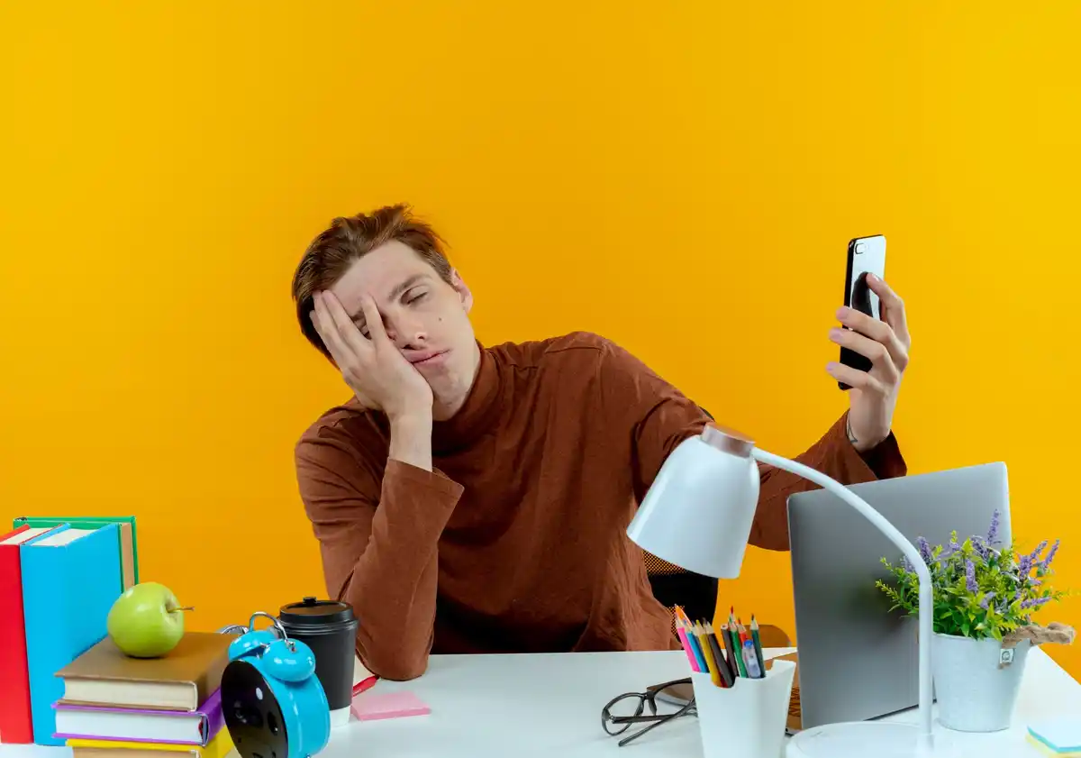 frustrated person multitasking at desk with laptop and phone