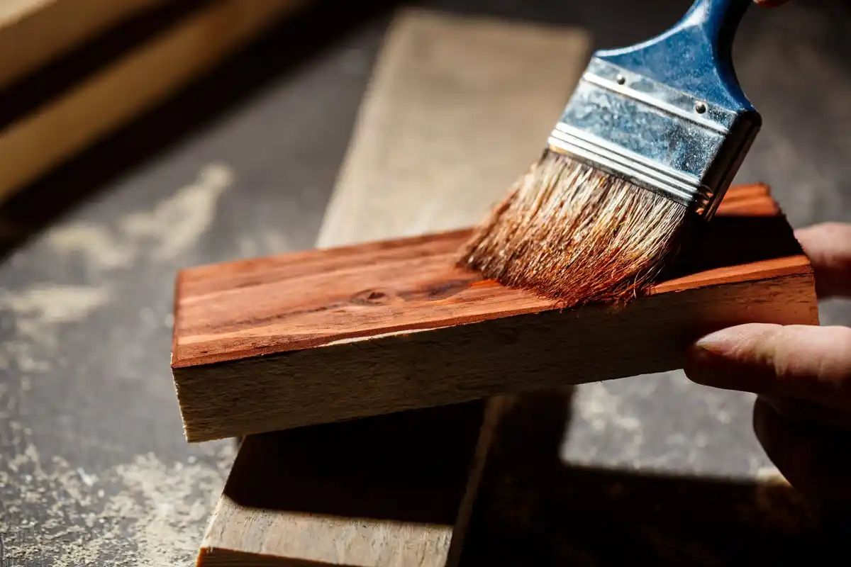 Close up of hands restoring wooden furniture with varnish brush