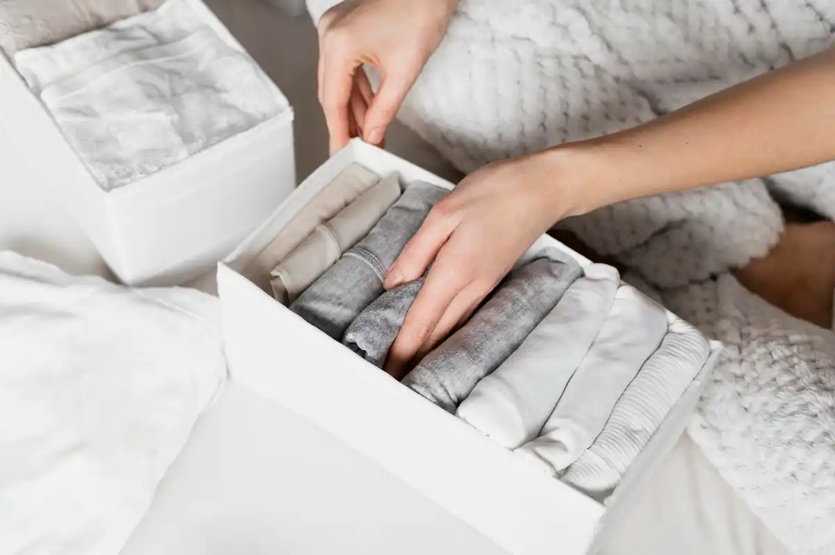 hands organizing clothes into storage boxes at home