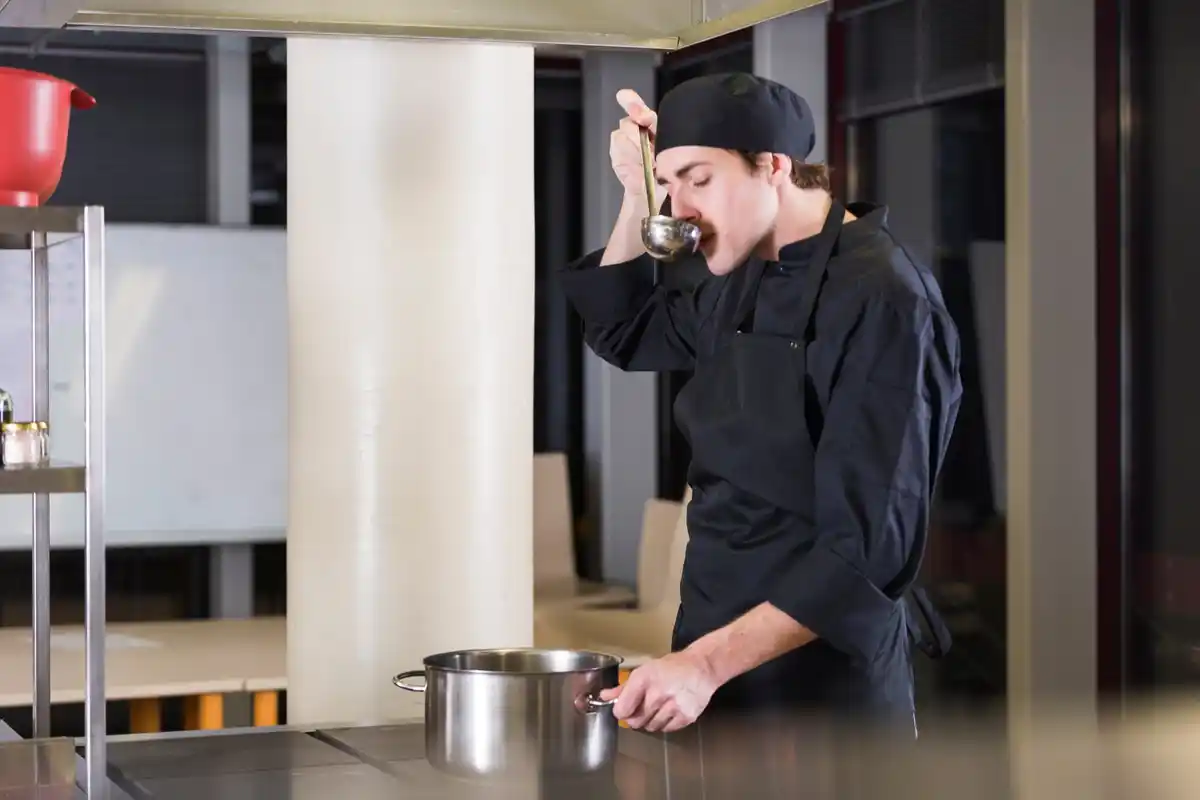 chef stirring sauce on stove kitchen interior