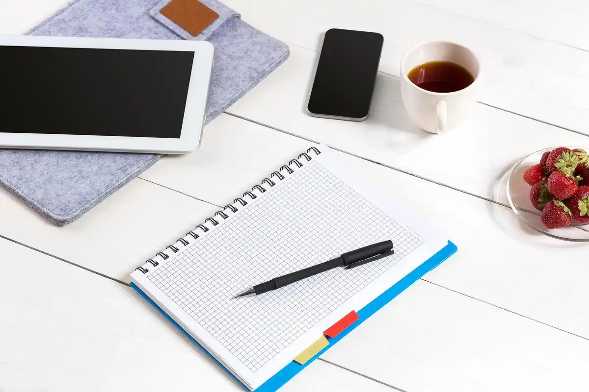 organized desk with notebook and smartphone coffee cup